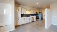 Located at 155 E 4th Place in Sioux Falls, South Dakota, this efficiently designed single-floor unit offers a thoughtfully laid-out living space that maximizes every square foot. The open-concept layout connects the main living area to a well-appointed kitchen, creating a cohesive and functional flow throughout. Polished concrete flooring runs through the main living and kitchen areas, lending an industrial-modern aesthetic that is both durable and visually striking.

The kitchen is a standout feature, outfitted with light wood shaker-style cabinetry extending to the ceiling for ample storage, a deep single-basin sink with a matte black faucet, and a full suite of stainless steel appliances including a refrigerator, range, microwave, and dishwasher. A bold navy blue subway tile backsplash adds a sharp contrast to the light cabinetry, while a pendant light above the workspace provides focused task lighting. Large windows in the living area invite abundant natural light, enhancing the open feel of the space.

The bathroom features warm wood-tone cabinetry, a white vessel sink, matte black hardware, and wood-look vinyl plank flooring, creating a clean and contemporary finish. A dedicated closet provides practical storage. The main living area is completed by a ceiling fan with integrated lighting and access to natural light through a well-placed window.