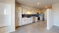 Located at 155 E 4th Place in Sioux Falls, South Dakota, this efficiently designed single-floor unit offers a thoughtfully laid-out living space that maximizes every square foot. The open-concept layout connects the main living area to a well-appointed kitchen, creating a cohesive and functional flow throughout. Polished concrete flooring runs through the main living and kitchen areas, lending an industrial-modern aesthetic that is both durable and visually striking.

The kitchen is a standout feature, outfitted with light wood shaker-style cabinetry extending to the ceiling for ample storage, a deep single-basin sink with a matte black faucet, and a full suite of stainless steel appliances including a refrigerator, range, microwave, and dishwasher. A bold navy blue subway tile backsplash adds a sharp contrast to the light cabinetry, while a pendant light above the workspace provides focused task lighting. Large windows in the living area invite abundant natural light, enhancing the open feel of the space.

The bathroom features warm wood-tone cabinetry, a white vessel sink, matte black hardware, and wood-look vinyl plank flooring, creating a clean and contemporary finish. A dedicated closet provides practical storage. The main living area is completed by a ceiling fan with integrated lighting and access to natural light through a well-placed window.