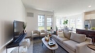 This single-floor residence offers a thoughtfully designed open-concept layout that seamlessly connects the main living areas. The welcoming entryway leads into a bright, airy living room lined with large windows that flood the space with natural light, offering views of the surrounding neighborhood. The living area features light wood-style flooring and flows naturally into the dining space, which is framed by expansive windows and elegant drapery, creating a comfortable setting for everyday meals or entertaining.

The kitchen is well-equipped with white shaker cabinetry, stainless steel appliances including a refrigerator with ice maker, range, microwave, and dishwasher, all complemented by granite countertops. A central island with bar seating and a rich dark wood base provides additional prep and dining space.

The two bedrooms are carpeted and filled with natural light from generously sized windows. Both offer a calm, restful atmosphere with views to the outdoors. The two bathrooms feature white cabinetry with black hardware, granite-topped vanities, wood-style flooring, and clean, neutral finishes throughout. A dedicated in-unit laundry room with a full-size washer and dryer adds everyday convenience. Overall, the space presents a clean, modern aesthetic with consistent finishes throughout.
