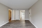 Located in Chattanooga, TN (37421), this single-floor unit offers a clean, updated interior with a consistent neutral color palette and wood-look vinyl plank flooring carried throughout every room. The open entryway and main living area provide a generous, well-proportioned space with natural light streaming through window blinds, creating a bright and welcoming atmosphere. The kitchen is equipped with white shaker-style cabinetry, light granite-look countertops, a double-basin sink, and a full suite of black appliances including a refrigerator, dishwasher, electric range, and over-the-range microwave. The bedrooms are well-sized, each featuring natural light from windows and access to closet storage. One bedroom includes a walk-in closet, while another features vertical shiplap-style wall paneling and a sliding glass door leading to an outdoor area. The bathroom presents a white vanity with ample counter space and wood-look flooring that ties into the rest of the unit. Textured ceilings in select rooms add a traditional touch, while crisp white trim and doors maintain a clean, modern finish. The overall layout is efficient and functional, making practical use of every area within the single-floor footprint.