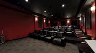 Located at 1047 E Lawn Dr in Forest, VA, this purpose-built home theater delivers a true cinematic experience within a single, well-appointed screening room. The space is designed with a dark, dramatic aesthetic, featuring deep red walls contrasted against a black ceiling that enhances the immersive atmosphere. Recessed lighting and wall-mounted sconces provide subtle, ambient illumination that replicates the feel of a professional movie theater.

The seating arrangement consists of multiple rows of plush black leather recliner chairs, organized in a tiered, stadium-style layout to ensure unobstructed sightlines from every seat. Each chair features integrated cup holders, adding a layer of comfort and convenience for viewers. A ceiling-mounted projector directs onto a large projection screen positioned at the front of the room, delivering a high-quality visual experience.

Acoustic treatment panels are strategically placed throughout the walls, optimizing sound quality and minimizing echo for a refined audio environment. Patterned carpet covers the floor throughout the room, contributing to both acoustics and comfort underfoot. A dedicated entry door with emergency exit signage is clearly visible, and a folding utility table near the rear wall adds functional versatility to the space. This theater is a well-engineered, detail-oriented screening environment suited for serious home entertainment.