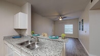 Located at 905 SH-499 Loop S in Harlingen, Texas, this single-floor residence offers a well-designed, functional layout finished with consistent, modern touches throughout. Wood-look plank flooring runs through the living areas, bedrooms, and bathrooms, providing a cohesive and easy-to-maintain aesthetic.

The open living area is bright and airy, benefiting from natural light through blinded windows and a ceiling fan overhead. It connects seamlessly to the kitchen via a peninsula counter, making the space feel open and ideal for everyday living. The galley-style kitchen is equipped with white cabinetry, granite countertops, a stainless steel sink, and white appliances including a refrigerator, electric range, microwave, and dishwasher — offering ample storage and prep space.

The unit includes two bathrooms, each featuring granite vanity countertops, white cabinetry, large mirrors, and a tub-shower combination. The clean, neutral color palette carries throughout both bathrooms, maintaining a tidy and functional feel.

A dedicated laundry area with washer and dryer hookups adds everyday convenience. The bedrooms are well-proportioned, each with ceiling fans and access to closet space, creating comfortable and practical retreats. Neutral gray-toned walls throughout the unit offer a versatile backdrop for any furnishing style.