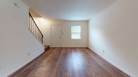 Located at 509 E Beal St in Henrico, Virginia, this two-floor home offers a clean, functional layout with consistent hardwood flooring that runs throughout both levels. The main floor entry welcomes you with rich, warm-toned hardwood floors and a staircase accented by a black metal railing, with a window that brings in natural light and a view of the surrounding greenery. The living area flows openly from the entryway, providing a versatile and well-proportioned space. The kitchen features white cabinetry, light countertops, a gas range, and a refrigerator, all arranged in a practical U-shaped layout with hardwood flooring underfoot. A full bathroom on the upper level includes a tub-shower combination, a vanity with white cabinetry, and tile flooring in a neutral tone. The upper floor hosts multiple bedrooms, each finished with light-toned hardwood floors, ceiling fans with integrated lighting, and windows that allow natural light to fill the rooms. The consistent use of neutral wall colors and wood flooring throughout creates a cohesive, easy-to-maintain interior. Overall, this home presents a straightforward and functional design well-suited for comfortable everyday living in the Henrico area.