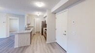 Located at 110-130 Edgar Lane in Sherwood Park, Alberta, this two-bedroom, two-bathroom unit offers a well-designed single-level layout with a clean, contemporary aesthetic. The open-concept living, dining, and kitchen area forms the heart of the unit, featuring light wood-look flooring, a textured ceiling, and a large window that invites natural light and views of the surrounding neighbourhood. The kitchen is appointed with granite-topped counters, a functional island with a double sink, light wood cabinetry, and a full suite of stainless steel appliances including a refrigerator, electric range with overhead microwave, and dishwasher. Both bathrooms share a consistent design language, each with granite vanity countertops, matching cabinetry, and a full tub-shower combination, complemented by wood-look flooring. The two bedrooms are carpeted for comfort, with windows providing natural light and neighbourhood views. Three closets offer generous storage throughout the unit. A dedicated laundry space houses a stacked front-load washer and dryer. The overall palette of white walls, neutral tones, and modern finishes creates a bright, functional, and move-in-ready living environment.