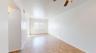 This single-story residence offers a practical and efficient layout across four bedrooms and two bathrooms. Wood-look flooring flows consistently throughout the entire home, creating a cohesive and easy-to-maintain aesthetic. The open kitchen and living area serves as the heart of the home, with the kitchen featuring light maple cabinetry, granite-style countertops, black appliances including a gas range, built-in microwave, dishwasher, and refrigerator, all illuminated by overhead lighting. The living area is bright and airy, benefiting from natural light through a large window and a ceiling fan overhead. The primary bedroom is generously sized, equipped with its own ceiling fan and a well-sized window that allows natural light to fill the room. The three additional bedrooms are well-proportioned, each featuring windows with blinds that provide both light and privacy. Both bathrooms are identically appointed with full tub-shower combinations featuring white tile surrounds, dark wood vanities, and the same warm wood-look flooring. A hallway connects the living spaces to the bedrooms and bathrooms, and a closet provides additional storage. The overall ambiance is clean, neutral, and move-in ready.