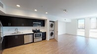 Located on Hollywood Boulevard in Los Angeles, this single-floor unit offers a contemporary, open-concept design with a clean, neutral aesthetic throughout. Light wood-style flooring extends across the main living and kitchen areas, creating a cohesive and airy feel.

The kitchen is well-appointed with dark espresso cabinetry that contrasts sharply against white subway tile backsplash and bright walls. A full suite of stainless steel appliances includes a refrigerator, electric range with oven, over-the-range microwave, and dishwasher. Ample upper and lower cabinetry provides generous storage, and recessed lighting illuminates the space effectively. A stacked washer and dryer unit is conveniently tucked adjacent to the kitchen.

The open living area is generously proportioned, featuring recessed and track lighting, crisp white walls, and a seamless flow from the kitchen. A dedicated entry door provides a clear sense of arrival.

The bedroom is carpeted and includes a ceiling fan with light fixture, a closet with a hanging rod, and direct access to the bathroom. The bathroom features a full soaking tub with shower, a dark-cabinet vanity with white countertop, and wood-style flooring, maintaining the modern palette found throughout the unit.