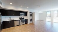 Located on Hollywood Boulevard in Los Angeles, this single-floor unit offers a contemporary, open-concept design with a clean, neutral aesthetic throughout. Light wood-style flooring extends across the main living and kitchen areas, creating a cohesive and airy feel.

The kitchen is well-appointed with dark espresso cabinetry that contrasts sharply against white subway tile backsplash and bright walls. A full suite of stainless steel appliances includes a refrigerator, electric range with oven, over-the-range microwave, and dishwasher. Ample upper and lower cabinetry provides generous storage, and recessed lighting illuminates the space effectively. A stacked washer and dryer unit is conveniently tucked adjacent to the kitchen.

The open living area is generously proportioned, featuring recessed and track lighting, crisp white walls, and a seamless flow from the kitchen. A dedicated entry door provides a clear sense of arrival.

The bedroom is carpeted and includes a ceiling fan with light fixture, a closet with a hanging rod, and direct access to the bathroom. The bathroom features a full soaking tub with shower, a dark-cabinet vanity with white countertop, and wood-style flooring, maintaining the modern palette found throughout the unit.