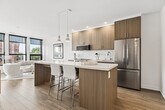 Located at 2946 Dundas Street West in Toronto's vibrant Junction neighbourhood, this 2-bedroom, 2-bathroom unit offers a well-designed, single-floor layout with a clean, contemporary aesthetic throughout. Large floor-to-ceiling windows with sleek black frames are a defining architectural feature, flooding the living spaces with natural light and framing views of the surrounding streetscape and brick buildings characteristic of the area.

The living room is bright and open, with light wood flooring, white walls, and corner windows that allow sunlight to pour in from multiple angles. The second bedroom features a sliding glass partition that connects it to the main living and kitchen area, offering flexibility and an open feel. The primary bedroom is equipped with expansive windows overlooking Dundas Street, providing a lively urban backdrop.

Both bathrooms are finished in a modern style — one features large-format grey tile with a soaker tub and shower combination, while the other offers a light wood vanity, square under-mount sink, and neutral tile flooring. Hallways connect the rooms efficiently, contributing to a practical and well-organized floor plan. Throughout the unit, the consistent use of light tones, quality finishes, and natural light creates a cohesive and inviting living environment.