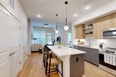 This thoughtfully designed 2-bedroom, 4-bathroom residence at 3305 South Blvd in Charlotte, NC offers a sleek, modern aesthetic throughout its well-appointed single-floor layout. The open-concept kitchen and living area serves as the heart of the home, anchored by a generous white-quartz waterfall island with seating, complemented by two-tone cabinetry in warm wood and matte gray, stainless steel appliances, and stylish globe pendant lighting. Warm hardwood-style flooring flows seamlessly throughout the space, enhancing the bright, airy ambiance created by large windows that invite abundant natural light into the living area. The primary bedroom is a comfortable retreat featuring a bold accent wall, walk-in closet with a custom built-in organization system, and a private en-suite bathroom with a glass-enclosed shower and sleek gray vanity. The second bedroom is a clean, minimalist space with its own distinctive character. Additional bathrooms are finished with modern gray cabinetry, white quartz countertops, large mirrors, and tiled tub-shower combinations. The residence also includes three closets, a dedicated laundry area, utility room, and a private balcony — offering a complete and functional living experience in the heart of Charlotte.
