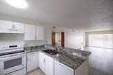 Located at 6475 Sea Wolf Ct in Naples, FL, this single-floor, three-bedroom, two-bathroom home offers a well-designed layout with a bright and open feel throughout. The kitchen is a standout feature, showcasing bold granite countertops, a peninsula with an undermount sink, white cabinetry, white appliances including a refrigerator and electric range, and tile flooring. It flows seamlessly into the combined dining and living area, which is finished with light wood-look flooring and a textured ceiling. A sliding glass door fills the living room with natural light and provides direct access to an outdoor balcony. The bedrooms are carpeted or wood-floored with neutral walls and ample natural light, while two closets provide dedicated storage space. The bathrooms feature granite vanity countertops, white cabinetry, tile flooring, and a tub-shower combo with classic white tile surround. A dedicated laundry area with a full-size washer and dryer is conveniently tucked behind charming louvered wood doors. A utility room and hallway complete the thoughtful floor plan. The home's clean, neutral palette and functional layout make it a comfortable and practical living space in Southwest Florida.