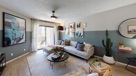 This well-appointed single-floor residence showcases a thoughtfully designed interior with a cohesive contemporary aesthetic. The living room serves as the heart of the home, featuring a striking two-tone wall treatment with a deep teal lower half, a textured ceiling, ceiling fan, and sliding glass doors that open to an outdoor patio, flooding the space with natural light. A curated gallery wall adds artistic character to the room.

The kitchen is outfitted with white upper cabinetry, dark lower cabinetry, tile backsplash, a peninsula with a white countertop breakfast bar, and a window above the sink for added natural light. A dedicated dining area adjacent to the kitchen features a bold geometric teal accent wall adorned with wall-mounted planters, creating a lively, nature-inspired atmosphere.

Both bedrooms are generously sized, each featuring a deep forest-green accent wall, ceiling fan, light wood-style flooring, and sliding glass doors leading to a private patio with outdoor views. One bedroom includes a walk-in closet. The bathroom is cleanly designed with a dark vanity, round mirror, globe lighting, and wood-style flooring. Throughout the residence, light wood flooring, textured ceilings, and consistent design elements create a unified and inviting ambiance.