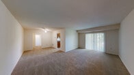 This single-story residence offers a well-organized layout across five bedrooms and two full bathrooms, providing ample space for larger households or shared living arrangements. The open living room is a standout feature, finished with neutral carpet and anchored by a ceiling fan. A large sliding glass door floods the space with natural light and offers views of surrounding greenery, creating a bright and welcoming atmosphere. The layout flows naturally from the living area into the kitchen, which is appointed with warm wood cabinetry, granite-style countertops, and black appliances including a refrigerator, range, and dishwasher, all set on durable tile flooring. The generously sized primary bedroom includes its own sliding glass door for outdoor access and natural light, along with a dedicated closet space. Additional bedrooms are carpeted and offer practical storage solutions. One bedroom notably includes an in-unit stacked washer and dryer with a closet alongside it — a convenient functional feature. Both bathrooms are finished consistently with tile flooring, wood vanities topped with granite-style counters, and mirrored medicine cabinets. One bathroom features a full tub-shower combination with tiled surround. Throughout, the neutral color palette and clean finishes provide a move-in ready environment.