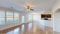 This two-story home in Austin, TX offers six bedrooms and four bathrooms spread across a generously sized layout. The main floor — the larger of the two levels — features an open-concept living and dining area with gleaming hardwood floors, crown molding, and abundant natural light pouring through multiple large windows fitted with blinds. A ceiling fan anchors the living space, which flows seamlessly into the kitchen. The kitchen is well-appointed with dark espresso cabinetry, granite-style countertops, a breakfast bar peninsula, black appliances, and recessed lighting. Carpeted staircases with clean white railings connect both floors. The upper level houses additional bedrooms, each finished with plush carpet, ceiling fans, crown molding, and closets. The spacious primary bedroom features vaulted ceilings and access to a walk-in closet outfitted with built-in shelving, double hanging rods, and carpeted flooring. Secondary bedrooms include closets with built-in shelving. The bathrooms are clean and functional, featuring tub-shower combinations with white tile surrounds and dark wood cabinetry. Hallways connect the rooms efficiently throughout both floors, and the home includes a dedicated laundry area, adding everyday convenience to this well-organized Austin residence.
