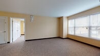 Located at 60 Ferry St in Middletown, Connecticut, this single-floor unit offers a well-organized and functional layout designed for comfortable everyday living. The living and bedroom areas are finished with neutral-toned carpet and painted in warm cream and yellow hues, creating a bright and welcoming atmosphere. Windows fitted with blinds allow natural light to filter in while providing views of the surrounding neighborhood. Each carpeted room features dark baseboards that provide a clean contrast to the light walls, and multiple closets — including louvered and double-door styles — offer generous storage throughout. The kitchen is equipped with white cabinetry, granite-style countertops, a gas range with overhead ventilation, a refrigerator, and hardwood-style flooring that carries through into the adjacent areas. The bathroom includes a white vanity with a granite-top sink, a full bathtub with shower, and matching hardwood-style flooring, providing a cohesive and polished finish. A dedicated laundry area accommodates a full-size washer and dryer side by side, complemented by wire shelving for additional storage and the same warm hardwood-style flooring. The overall layout, as seen from the dollhouse view, is thoughtfully arranged with clear separation between living, sleeping, and utility spaces.