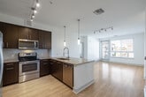 Located at 4440 Twain Ave, Unit 435 in San Diego, CA, this well-appointed single-floor residence offers a thoughtfully designed layout with modern finishes throughout. The open-concept kitchen is a standout feature, showcasing dark espresso cabinetry, granite countertops, a stylish tile backsplash, and a full suite of stainless steel appliances including a refrigerator, range, microwave, and dishwasher. A large island with pendant lighting and a professional-style faucet anchors the space, flowing seamlessly into the bright living area with light wood-style flooring and access to a private balcony. The balcony offers elevated views of the landscaped courtyard and surrounding community, framed by mature palm trees and clear San Diego skies. The bedrooms are finished with plush carpeting and receive generous natural light through wide windows fitted with horizontal blinds. A spacious walk-in closet with wire shelving provides ample storage. The bathroom is well-appointed with a deep soaking tub surrounded by clean white tile and brushed nickel fixtures. Track lighting and ceiling fans are featured throughout, contributing to a clean, contemporary ambiance well-suited for comfortable everyday living.