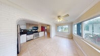 Located at 1920 Northeast 3rd Street in Deerfield Beach, Florida, this single-story, two-bedroom, one-bathroom home offers a practical and characterful layout. The open-concept living and kitchen area is one of the home's standout features, connected by a distinctive painted white brick archway that adds architectural charm. The living area is finished with large neutral ceramic tile flooring, crown molding, and a ceiling fan, while multiple windows allow natural light to flow in and provide pleasant outdoor views.

The kitchen is well-equipped with stainless steel appliances including a range, dishwasher, and refrigerator, complemented by dark granite countertops, a mix of white lower cabinetry and taupe upper cabinets, and a dark tile backsplash. A window above the sink brings in additional natural light.

The primary bedroom features warm hardwood flooring, a vibrant teal accent wall, a wall-mounted AC unit, and a walk-in closet with built-in shelving. The second bedroom is finished with tile flooring, a ceiling fan with light fixture, a window, and an adjacent storage area. Throughout the home, crown molding and ceiling fans are consistent details that contribute to a cohesive, functional living environment.