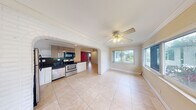 Located at 1920 Northeast 3rd Street in Deerfield Beach, Florida, this single-story, two-bedroom, one-bathroom home offers a practical and characterful layout. The open-concept living and kitchen area is one of the home's standout features, connected by a distinctive painted white brick archway that adds architectural charm. The living area is finished with large neutral ceramic tile flooring, crown molding, and a ceiling fan, while multiple windows allow natural light to flow in and provide pleasant outdoor views.

The kitchen is well-equipped with stainless steel appliances including a range, dishwasher, and refrigerator, complemented by dark granite countertops, a mix of white lower cabinetry and taupe upper cabinets, and a dark tile backsplash. A window above the sink brings in additional natural light.

The primary bedroom features warm hardwood flooring, a vibrant teal accent wall, a wall-mounted AC unit, and a walk-in closet with built-in shelving. The second bedroom is finished with tile flooring, a ceiling fan with light fixture, a window, and an adjacent storage area. Throughout the home, crown molding and ceiling fans are consistent details that contribute to a cohesive, functional living environment.