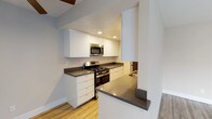 Located in the desirable 90046 zip code of Los Angeles, this single-floor residence on N Alta Vista Blvd presents a thoughtfully updated interior with a cohesive, contemporary design. The living area features light wood-style flooring, a ceiling fan, and a fireplace, creating a welcoming atmosphere with natural light filtering through vertical blinds. A half-wall pass-through seamlessly connects the living space to the kitchen, which is outfitted with crisp white cabinetry, gray quartz-style countertops, and a full suite of stainless steel appliances, including a gas range, microwave, refrigerator, and dishwasher. Light hardwood flooring continues throughout the kitchen, enhancing the bright, open feel. The bedrooms are carpeted for comfort and feature generous closet space, including a mirrored sliding-door closet with built-in shelving. The bathroom is cleanly finished with a white vanity, gray countertop, and a full tub-shower combination. Neutral tones, recessed lighting, and consistent finishes throughout give the space a polished, move-in-ready character well-suited to the vibrant West Hollywood-adjacent neighborhood.