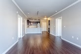 This single-floor residence offers a well-designed open-concept layout that seamlessly connects the living, dining, and kitchen areas. The living space features rich, dark hardwood flooring that extends throughout the main areas, complemented by neutral gray walls and crisp white crown molding. Track lighting and multiple windows provide both natural and artificial illumination, creating a bright and welcoming atmosphere.

The kitchen is a standout feature, equipped with dark espresso cabinetry, granite countertops, and a full suite of stainless steel appliances, including a refrigerator, range, and microwave. A large central island with an undermount sink and pendant lighting above serves as both a functional workspace and a visual centerpiece. A dedicated built-in wine rack adds a refined touch near the kitchen.

The bedrooms are carpeted for comfort and receive natural light through blinded windows. The primary bedroom includes access to a walk-in closet and an en-suite bathroom. Bathrooms throughout feature dark cabinetry with granite vanity tops, hardwood-style flooring, and a tub-shower combination. The overall design maintains a cohesive, modern aesthetic with consistent finishes across all rooms.