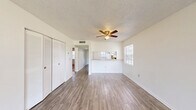 Located in Lake Wales, FL, this single-story, one-bedroom, one-bathroom home offers a practical and efficient layout. The combined dining and living area is bright and open, featuring light laminate wood flooring, a ceiling fan, and natural light from multiple windows. A pass-through counter connects the living area to the kitchen, which is equipped with white cabinetry, wood-toned countertops, an electric range, a dishwasher, and a double-basin sink beneath a window. A central hallway with a skylight connects the main living spaces to the private areas of the home, with laminate flooring extending throughout. The bedroom is carpeted and generously proportioned, featuring dual closets with louvered bifold doors and a large window that invites natural light. The full bathroom includes a tiled tub-shower combination, a toilet, and a vanity. Additional spaces include a utility room, laundry area, and two closets for ample storage. The dining area opens via sliding glass doors to a patio, offering pleasant views of the surrounding greenery — a welcoming outdoor retreat ideal for the Florida lifestyle.