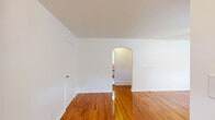 Located at 7 Laurel Dr in Scranton, PA, this one-bedroom, one-bathroom unit offers a well-organized, single-floor layout designed for comfortable everyday living. Gleaming hardwood floors run throughout the main living areas, lending warmth and a classic character to the space.

The living room is generously sized, featuring bright white walls, a flush ceiling light fixture, and a welcoming entryway with a paneled front door accented by transom windows that invite natural light. A radiator unit provides efficient heating. An elegant arched doorway connects the living area to the hallway, adding a subtle architectural detail that enhances the flow of the space.

The bedroom is a comfortable, well-proportioned room with the same polished hardwood flooring, a window overlooking greenery, and a radiator for climate control. The light tones of the walls keep the room feeling open and airy.

The bathroom is tiled in classic grey and white, featuring a wooden vanity with a white countertop sink, a lighted mirror, a window for natural ventilation, mosaic tile flooring, and a full bathtub — all contributing to a clean, functional design.

The kitchen and hallway complete the layout, with light tile flooring in the entry area providing a practical transition zone. Overall, the unit offers a tidy, functional living environment with timeless finishes throughout.