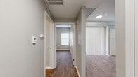 Located at 195 E Round Grove Rd in Lewisville, TX, this single-floor residence offers a smartly designed layout with one bedroom, one bathroom, a kitchen, closet, hallway, and utility room. Wood-look flooring flows consistently throughout every room, lending a warm, cohesive aesthetic to the entire space. The kitchen is well-equipped with stainless steel appliances — including a range, microwave, and dishwasher — complemented by crisp white shaker cabinetry, white quartz countertops, a subway tile backsplash, and a stainless steel sink. A mirrored pass-through opens the kitchen to the living area, which features crown molding and dual ceiling vents. The living space connects to a hallway lined with neutral gray walls and white trim, leading to the bedroom and bathroom. The spacious primary bedroom is fitted with a ceiling fan, plantation shutters, and multiple doorways providing access to the closet, bathroom, and hallway. The bathroom offers a wide vanity with white cabinetry, quartz countertops, an expansive mirror, and overhead storage. A dedicated utility room adds everyday practicality. Throughout the home, a consistent neutral gray palette, white trim, and modern fixtures create a clean, move-in-ready environment.