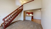 Located at 5591 Rustling Way Ln. in Columbus, OH, this two-bedroom, two-bathroom two-story home offers a well-designed layout spread across two floors. The main level serves as the heart of the home, anchored by an impressive vaulted living room with soaring ceilings, a ceiling fan, and plush carpeting. A rich wood-railed staircase rises dramatically from the living area, adding a warm architectural focal point. The kitchen is efficiently laid out with warm cherry-toned cabinetry, granite-style countertops, a breakfast bar peninsula, and wood-look flooring, with white appliances including a refrigerator and range. Both bathrooms are well-appointed with matching cherry wood vanities, granite-style countertops, tub/shower combos, and wood-look flooring. The upper level hosts the bedrooms, each featuring carpet flooring, neutral walls, and windows that bring in natural light. The spacious primary bedroom offers generous room proportions. Five closets throughout the home provide abundant storage. A dedicated laundry room with utility hookups, wood-look flooring, and shelving adds everyday convenience. A utility room rounds out the home's functional offerings, making this a practical and comfortable two-story residence.