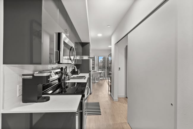 Galley-style kitchen with modern appliances and open layout. - The Ruby Apartments