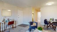 This single-floor residence offers a thoughtfully designed layout that balances comfort and functionality. The open living area is generously sized, featuring soft carpeting, neutral wall tones, and a bright window that draws in natural light and provides views of the surrounding neighborhood. The space accommodates a full seating arrangement with ease, creating a welcoming environment for relaxing or entertaining.

Adjacent to the living area is a dedicated dining nook, sized comfortably for a round dining table and chairs — ideal for everyday meals or casual gatherings. The kitchen is outfitted with white shaker-style cabinetry, a classic subway tile backsplash, light countertops, and stainless steel appliances including a gas range and over-the-range microwave. Light wood-style flooring and a matte black faucet add modern contrast to the bright, clean aesthetic.

The bedroom is a calm retreat, featuring carpet flooring, a large window with blinds for natural light and privacy, and a closet with louvered doors. The layout connects smoothly back to the main living space. The bathroom is finished with neutral tile flooring and includes a shower-tub combination, maintaining a clean and functional design consistent with the rest of the residence.