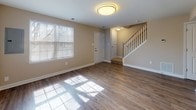 Located at 10560 Tralee Terrace in Damascus, Maryland, this two-floor residence offers a well-organized layout with distinct living spaces across both levels. The main floor welcomes visitors with a bright, open living area featuring warm hardwood-style flooring, neutral-toned walls, and large windows that allow generous natural light to pour in. A staircase with a classic white balustrade connects the two levels seamlessly.

The kitchen is a functional and attractive space, outfitted with warm honey-toned cabinetry, light granite countertops, a subway tile backsplash, and a full suite of black appliances including a gas range, over-the-range microwave, refrigerator, and dishwasher. Hardwood-style flooring continues throughout, complementing the kitchen's clean, contemporary aesthetic.

The upper level hosts multiple bedrooms, each finished with plush neutral carpeting and windows that bring in natural light. The primary bedroom is notably spacious, featuring dual windows and a double-door closet. Additional bedrooms offer a comfortable and versatile footprint.

Bathrooms are finished with warm tile flooring and white subway tile surrounds accented by a decorative mosaic tile inset in the tub and shower areas, adding a refined touch to each bathroom's clean, practical design.