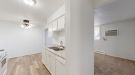 Located at 620 Gorman St in Shakopee, Minnesota, this single-floor, 2-bedroom, 1-bathroom residence offers a practical and well-organized layout. The galley-style kitchen is a standout feature, showcasing white cabinetry, granite-look countertops, a double sink, and white appliances including a gas range and refrigerator. Warm wood-look flooring runs throughout the kitchen, which connects seamlessly to the hallway and living areas. Both bedrooms are carpeted and bright, benefiting from natural light through large windows dressed with vertical blinds. Each bedroom includes generous louvered bi-fold closets offering ample storage. Baseboard heating is present throughout, and one bedroom also features a wall-mounted air conditioning unit. The bathroom is clean and classic, with fully tiled walls surrounding a soaking bathtub. A connecting hallway ties the rooms together efficiently. The overall interior palette is neutral and bright, with white walls and light-toned finishes throughout, creating a clean and easy-to-personalize living environment. The layout maximizes the use of the available floor space, making the residence comfortable and livable.