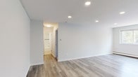 Located at 6451–6461 Oxford Avenue in Philadelphia's Fox Chase neighborhood, this single-floor unit combines contemporary updates with a clean, functional layout. The living areas feature light gray luxury vinyl plank flooring that runs throughout, complemented by recessed lighting that creates a bright, modern atmosphere. Large windows in the main living space allow natural light to filter in while providing views of surrounding greenery, and a wall-mounted air conditioning unit and baseboard heating ensure year-round comfort.

The kitchen stands out with rich, dark espresso cabinetry offering ample upper and lower storage, marble-look countertops, a stainless steel sink, and a textured tile backsplash that adds visual interest. The overall design strikes a balance between practicality and style.

The bedroom is carpeted for warmth and comfort, featuring a generously sized double-door closet and baseboard heating. A window allows natural light into the room. The bathroom is finished with clean white subway tile surrounding the tub and shower area, accented by a decorative mosaic border in black, white, and metallic tones, lending a polished, updated feel. The neutral color palette carried throughout the unit creates a cohesive, move-in-ready environment.