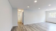 Located at 6451–6461 Oxford Avenue in Philadelphia's Fox Chase neighborhood, this single-floor unit combines contemporary updates with a clean, functional layout. The living areas feature light gray luxury vinyl plank flooring that runs throughout, complemented by recessed lighting that creates a bright, modern atmosphere. Large windows in the main living space allow natural light to filter in while providing views of surrounding greenery, and a wall-mounted air conditioning unit and baseboard heating ensure year-round comfort.

The kitchen stands out with rich, dark espresso cabinetry offering ample upper and lower storage, marble-look countertops, a stainless steel sink, and a textured tile backsplash that adds visual interest. The overall design strikes a balance between practicality and style.

The bedroom is carpeted for warmth and comfort, featuring a generously sized double-door closet and baseboard heating. A window allows natural light into the room. The bathroom is finished with clean white subway tile surrounding the tub and shower area, accented by a decorative mosaic border in black, white, and metallic tones, lending a polished, updated feel. The neutral color palette carried throughout the unit creates a cohesive, move-in-ready environment.