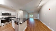 Located at 499 Boston Rd in Billerica, MA, this well-appointed 2-bedroom, 2-bathroom single-floor residence offers a thoughtfully designed layout with quality finishes throughout. The open-concept kitchen and living area serves as the heart of the home, featuring rich hardwood flooring, a center island with dark granite countertops, white shaker cabinetry, and a full suite of stainless steel appliances including a refrigerator, range, and built-in microwave. The adjoining living room is bright and spacious, with natural light streaming in through large windows that frame lush, tree-lined views. Both bedrooms are carpeted for comfort, with the primary bedroom offering generous dimensions and direct access to its own closet. Three closets in total provide ample storage throughout the residence. The two bathrooms are finished consistently with white vanity cabinetry, dark granite countertops, tile flooring, and well-lit mirrors. One bathroom features a full soaking tub with tiled surround. A dedicated in-unit laundry room accommodates a full-size side-by-side washer and dryer. The overall aesthetic is clean and neutral, with soft wall tones and white trim creating a cohesive, move-in-ready environment.