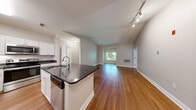 Located at 499 Boston Rd in Billerica, MA, this well-appointed 2-bedroom, 2-bathroom single-floor residence offers a thoughtfully designed layout with quality finishes throughout. The open-concept kitchen and living area serves as the heart of the home, featuring rich hardwood flooring, a center island with dark granite countertops, white shaker cabinetry, and a full suite of stainless steel appliances including a refrigerator, range, and built-in microwave. The adjoining living room is bright and spacious, with natural light streaming in through large windows that frame lush, tree-lined views. Both bedrooms are carpeted for comfort, with the primary bedroom offering generous dimensions and direct access to its own closet. Three closets in total provide ample storage throughout the residence. The two bathrooms are finished consistently with white vanity cabinetry, dark granite countertops, tile flooring, and well-lit mirrors. One bathroom features a full soaking tub with tiled surround. A dedicated in-unit laundry room accommodates a full-size side-by-side washer and dryer. The overall aesthetic is clean and neutral, with soft wall tones and white trim creating a cohesive, move-in-ready environment.