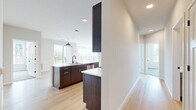 This well-appointed 2-bedroom, 2-bathroom residence in Madison, Wisconsin offers a thoughtfully designed single-floor layout with modern finishes throughout. The open-concept kitchen and living area serves as the heart of the home, featuring rich dark wood cabinetry, sleek white quartz countertops, stainless steel appliances including a refrigerator, electric range, microwave, and dishwasher, and a generous kitchen island with an undermount sink and pendant lighting overhead. Light hardwood flooring flows throughout the main living areas, enhancing the bright and airy atmosphere. The living room benefits from an expansive bank of windows that invite ample natural light and offer views of the surrounding neighborhood. Both bedrooms are carpeted for comfort, with the primary bedroom featuring a ceiling fan and large windows. The two bathrooms are finished in a contemporary style with light wood vanities, white quartz countertops, LED-backlit mirrors, black matte hardware accents, glass-enclosed showers, and hardwood-style flooring. A dedicated in-unit laundry room provides added convenience with shelving and a full-size washer and dryer. The overall design aesthetic is clean, modern, and move-in ready.