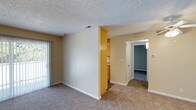 This single-floor, 1-bedroom, 1-bathroom residence offers a well-organized layout designed for comfortable everyday living. The main living area features neutral-toned carpet flooring, warm beige walls, and a textured ceiling that adds a classic touch to the space. A sliding glass door floods the living room with natural light while providing direct access to an outdoor balcony or patio area, enhancing the sense of openness. A partial wall divides the living space from the kitchen area, which features warm wood-toned cabinetry offering ample storage. The kitchen is efficiently arranged and connects seamlessly to the rest of the unit. A hallway leads to the bedroom, which is finished with carpeted flooring and painted in a soft, calming hue, creating a restful retreat. The layout is straightforward and functional, making efficient use of the available space throughout. With its neutral color palette, practical storage solutions, and access to the outdoors, this residence provides a comfortable and inviting environment suited for single occupancy or a small household.