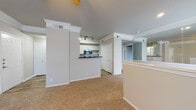 This single-floor residence offers a thoughtfully designed layout that balances comfort and functionality throughout. The open-concept living and dining area is finished with warm, neutral-toned carpet and features decorative crown molding, a ceiling fan with light fixture, and a sliding glass door that opens to a balcony, allowing natural light to flow freely into the space. A half-wall partition with white trim elegantly defines the transition between living areas while maintaining an airy, connected feel.

The kitchen is equipped with stainless steel appliances, including a refrigerator, electric range, and microwave, all complemented by white cabinetry, a subway tile backsplash, dark marble-style countertops, and wood-look flooring. A breakfast bar overlooks the living area, making the kitchen ideal for both cooking and entertaining.

The bedrooms are carpeted and generously sized, each outfitted with ceiling fans and windows fitted with blinds. The primary bedroom includes access to a walk-in closet, providing ample storage. The bathroom is a standout feature, offering a long dual-sink vanity with dark marble-style countertops, white cabinetry, large mirrors, and wood-look flooring, creating a clean and practical space. Throughout, the neutral color palette and consistent finishes lend the residence a cohesive, welcoming ambiance.