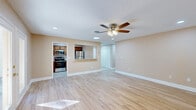Located at 2 Hollandale Ln in Clifton Park, NY, this well-appointed single-floor home offers a comfortable and functional layout. The open-concept living room is a standout feature, showcasing light hardwood floors, neutral warm-toned walls, recessed lighting, and a ceiling fan that adds both style and practicality. French doors flood the living area with natural light and provide direct views of the lush outdoor surroundings. The kitchen connects seamlessly to the living space via a granite-topped pass-through bar, making it ideal for entertaining. It features rich warm-toned wood cabinetry, granite countertops, a classic subway tile backsplash, tile flooring, and a full suite of stainless steel appliances including a refrigerator, range, microwave, and dishwasher. A window above the sink brings in additional natural light. The generously sized bedroom continues the hardwood flooring theme and is fitted with a ceiling fan, recessed lighting, and a window offering outdoor views. Three closets throughout the home provide ample storage. The textured ceilings and clean white trim throughout lend a cohesive, polished feel to the entire space.