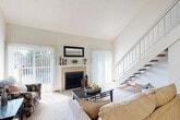 Located in Saint Charles, Missouri, this two-story, 3-bedroom, 2-bathroom home offers a well-designed layout spread across two floors. The main level is the larger of the two, featuring an open-concept living and dining area anchored by a tile-surround fireplace and soaring vaulted ceilings that lend an airy, expansive feel. Large sliding glass doors flood the living room with natural light and provide access to the outdoors. The kitchen is positioned just off the living area, offering warm wood cabinetry, tile flooring, and white appliances including a refrigerator, range, and built-in microwave. Soft carpet flows throughout the main living spaces and bedrooms. A hallway on the main floor connects the bedrooms, including a spacious primary suite. The two bathrooms feature tile flooring, wood-front vanities, and tub-shower combinations. Upstairs, a secondary loft-style living room overlooks the staircase and offers a cozy, versatile retreat. The upper level also provides access to additional rooms. Throughout the home, textured ceilings, neutral tones, and consistent finishes create a cohesive and comfortable atmosphere well-suited for everyday living.