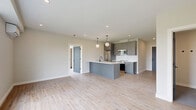 Located at 137-145 N Chestnut St in New Paltz, NY, this thoughtfully designed 3-bedroom, 2-bathroom unit offers a clean, modern aesthetic across a single floor. Light-toned hardwood flooring flows throughout, complementing the neutral palette of warm white walls and charcoal-gray interior doors with matte black hardware.

The kitchen serves as a centerpiece of the home, featuring a large quartz-topped island with an undermount sink and pendant globe lighting, gray flat-front cabinetry extending to the ceiling, a white tile backsplash, and a full suite of stainless steel appliances. The layout connects seamlessly to the living area, creating an open, functional flow.

The primary bedroom is generously proportioned, filled with natural light from large gridded windows that frame views of the surrounding greenery. The additional bedrooms are equally well-lit, with one featuring a wall-mounted mini-split unit for individual climate control.

Both bathrooms exhibit refined, contemporary finishes. The primary bathroom includes a floating double-vanity with light wood cabinetry, dual framed mirrors, brass sconce lighting, and large-format gray tile flooring. The secondary bath offers a soaking tub, a wall-mounted sink, white subway tile surround, and coordinating gray tile floors. The overall ambiance is clean, bright, and move-in ready.