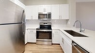 Located at 10135 Gate Parkway North in Jacksonville, FL, this efficiently designed 690-square-foot, one-bedroom, one-bathroom apartment offers a clean, modern aesthetic throughout its single floor. Wood-look flooring runs consistently through every room, providing a warm and cohesive feel. The open-concept kitchen and living area serves as the heart of the unit, featuring white shaker-style cabinetry, a classic subway tile backsplash, light quartz countertops with a peninsula breakfast bar, and a full suite of stainless steel GE appliances including a refrigerator, range, microwave, and dishwasher. The living room is bright and airy, benefiting from natural light through windows with blinds, crown molding, and a ceiling fan. The 150-square-foot primary bedroom is well-proportioned, highlighted by an arched window that frames outdoor greenery, along with a ceiling fan for added comfort. A dedicated walk-in closet with wire shelving provides ample storage. The bathroom is outfitted with a full tub/shower combination, stainless grab bars, a white vanity with sink, and wood-look flooring. Additional spaces include an entrance, hallway, and closet, completing this thoughtfully laid-out apartment.