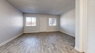 Located at 2025 W Indian School Rd in Phoenix, Arizona, this efficiently designed single-floor unit offers a thoughtful layout that maximizes every square foot. The open combined kitchen and living area serves as the heart of the space, bathed in natural light through multiple windows fitted with blinds. The living area features light wood-look plank flooring, neutral gray walls with painted brick detailing, and a textured ceiling that adds depth to the room. A front entry door is flanked by two windows, creating a bright and welcoming atmosphere. The kitchen is well-appointed with crisp white shaker-style cabinetry, a stainless steel refrigerator, a stainless sink, and a stylish gray subway tile backsplash set against white quartz-look countertops — a clean, contemporary aesthetic throughout. The bathroom is functional and neatly finished, offering a full tub and shower combo in white, complemented by wood-look flooring that carries the cohesive design language from the main living area. The unit's consistent use of light tones, modern fixtures, and updated finishes gives the space a fresh, move-in-ready feel suited for comfortable urban living in the heart of Phoenix.