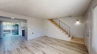This two-story home offers a clean, modern aesthetic across two well-proportioned floors. The main level features an open living room bathed in natural light, with light-toned luxury vinyl plank flooring that flows seamlessly throughout the space. A sleek staircase with black metal railings connects the levels, serving as a functional design focal point. The combined kitchen and dining area is outfitted with white cabinetry and stainless steel appliances, with a sliding glass door providing direct access to an outdoor patio and fenced backyard surrounded by mature landscaping. In-unit laundry is conveniently located on the main floor, housed in a dedicated closet with built-in shelving above the washer and dryer. The upper level hosts both bedrooms, each featuring light walls, vinyl plank flooring, and natural light from windows with views of the surrounding neighborhood. The primary bedroom is generously sized and offers dual closets for substantial storage. The second bedroom also includes a closet. The shared full bathroom is finished with a marble-style tile surround in the tub/shower combo, white vanity cabinetry, and coordinating light flooring. With four closets throughout, this home provides practical storage solutions alongside its bright, neutral design palette.