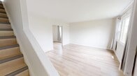 This two-storey, 3-bedroom, 2-bathroom home in Calgary, AB offers a clean and functional layout spread across two well-proportioned floors. Light-toned hardwood flooring runs throughout the home, complementing crisp white walls and creating a bright, cohesive aesthetic.

The main floor houses the kitchen and living room. The kitchen features white shaker-style cabinetry extending to the ceiling, ample countertop space, a white electric range, and a single-basin sink — all finished with black hardware accents. A staircase is conveniently accessible from the kitchen. The adjacent living room is open and airy, offering a generous footprint ideal for everyday living.

Upstairs, three bedrooms provide comfortable accommodation. The primary bedroom is a well-sized room featuring built-in shelving and a curtained window. The two additional bedrooms each include windows with outdoor views of the surrounding neighbourhood's mature trees, fitted with neutral curtain panels that allow natural light to filter in. Each room benefits from the consistent light hardwood flooring found throughout the home.

A hallway connects the upper-floor rooms, maintaining an efficient flow between spaces. The overall design is minimal and neutral, offering a clean canvas throughout.
