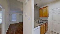 This thoughtfully designed single-floor unit offers an efficient and comfortable layout across one bedroom and one bathroom. The open-concept living and kitchen area serves as the heart of the home, where warm wood-look hardwood flooring, vaulted ceilings, and a ceiling fan create an airy and inviting atmosphere. Crown molding and chair rail detailing lend a classic architectural character to the living space, which is filled with natural light streaming through multiple windows fitted with blinds. A glass-paneled front door with a transom window above further enhances the bright, welcoming ambiance.

The kitchen is separated from the living area by a half-wall pass-through counter, ideal for casual dining or entertaining. It is equipped with warm honey-toned wood cabinetry, granite countertops, a stainless steel sink, a white electric range, a built-in microwave, a dishwasher, and a refrigerator, all complemented by pendant lighting overhead.

The bedroom offers a comfortable retreat with plush carpeting, crown molding, a large closet with panel doors, and generous natural light from a wide window. A built-in desk area adds functional versatility to the space.

The bathroom features granite countertops, warm wood cabinetry, a framed mirror with lighted vanity, tile flooring, and ample overhead storage, completing this well-appointed home.