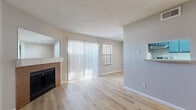 This 1-bedroom, 2-bathroom unit in Killeen, TX offers a practical and comfortable layout designed to maximize every square foot. The living room serves as the heart of the home, showcasing light wood-style flooring, a textured ceiling, and a tile-surround fireplace that adds a warm focal point to the space. Vertical blinds cover a large sliding glass door, allowing generous natural light to fill the room while providing access to the outdoors. The kitchen is positioned adjacent to the living area in an open pass-through configuration, featuring navy-toned cabinetry and light countertops. The bedroom is a comfortably sized retreat with a ceiling fan, a window with natural light, and direct access to the primary bathroom. The primary bathroom offers an extended vanity with dual mirrors, navy cabinetry, and wood-style flooring, providing ample storage and counter space. A second bathroom includes a full tub-shower combo with clean white tile surround. A dedicated closet provides additional storage. Neutral gray walls and consistent light wood flooring throughout the unit create a cohesive, move-in-ready aesthetic well-suited for comfortable everyday living.