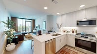 Located in the heart of Buckhead at 340 E Paces Ferry Rd NE, Atlanta, this well-appointed 2-bedroom, 2-bathroom residence offers a thoughtfully designed single-level layout with contemporary finishes throughout. The open-concept kitchen and living area serves as the heart of the home, where a sleek kitchen impresses with tall white cabinetry extending to the ceiling, stainless steel appliances including a gas range and French door refrigerator, a crisp white quartz peninsula with bar seating, and under-cabinet lighting. Light wood-tone flooring flows seamlessly through the space. The living room is bathed in natural light through expansive floor-to-ceiling windows that frame sweeping city views of the Buckhead skyline, creating a bright and airy atmosphere. The primary bedroom features large windows, neutral-toned grasscloth accent wall, and a dedicated walk-in closet with built-in shelving. The en-suite primary bathroom offers a long vanity with ample storage and tile flooring. The second bedroom is equally well-lit with generous closet space. A second full bathroom includes a soaking tub with tiled surround. A connecting hallway ties the layout together with efficient flow, making this an elegant and functional urban residence.