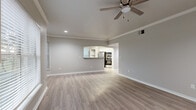This single-story home offers four bedrooms and four bathrooms across a well-designed floor plan. The open-concept living and dining area is a standout feature, finished with light wood-tone flooring, crown molding, and a ceiling fan. Large windows fitted with horizontal blinds allow ample natural light to fill the space. A tile-surround fireplace anchors one end of the living room, adding a warm focal point to the interior.

The kitchen is accessible via an arched passthrough and features a breakfast bar, stainless steel appliances including a built-in oven and microwave, and white cabinetry with open shelving — offering both functionality and a clean aesthetic.

The bedrooms are generously proportioned, with the primary bedroom providing a comfortable retreat. A spacious walk-in closet with built-in shelving and double hanging rods provides extensive storage. Additional closet space is available throughout the home.

Each of the four bathrooms is cleanly finished, with at least one featuring a tiled tub-shower combination. The hallways connect the rooms efficiently, contributing to a smooth and practical layout throughout.

The attached garage offers a wide, open concrete-floored space suitable for vehicles or additional storage, with an automatic door opener installed. Overall, the home presents a neutral, move-in-ready aesthetic with consistent finishes throughout.