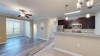 Located at 1006 Cider Mill Loop in Weaverville, NC, this well-appointed single-floor, 2-bedroom, 3-bathroom home offers a thoughtfully designed layout that maximizes both comfort and functionality. The open-concept living area flows seamlessly from the living room into a combined dining and kitchen space, all finished with durable hardwood-style flooring and neutral warm-toned walls. Crown molding and ceiling fans add refined detail to the main living spaces. The kitchen is a standout feature, boasting rich dark cabinetry, granite-style countertops, stainless steel appliances including a refrigerator, range, and microwave, and elegant pendant lighting over the breakfast bar. Tile flooring grounds the kitchen and dining area. A separate living room offers direct outdoor access through French doors framed by natural light, with views of an outdoor deck. The spacious primary bedroom includes two dedicated closets with wire shelving systems for ample storage. The bathrooms feature tile flooring and clean, neutral finishes. A dedicated laundry room with hook-ups and additional shelving adds everyday convenience. With two closets, three full bathrooms, and thoughtful finishes throughout, this home delivers practical, comfortable living in a serene Weaverville setting.